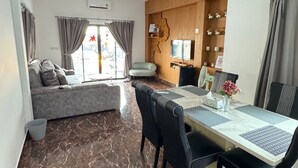 Una sala de estar moderna con un sofá, una mesa de comedor con sillas y una cocina con armarios de madera.