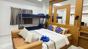 Un dormitorio moderno con una cama grande, un sofá, una cama litera y un cabecero de madera.