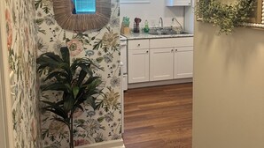 A kitchen with white cabinets, a window, and a welcome sign.