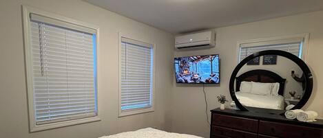 A bedroom with a bed, a dresser, a television, and a ceiling light.