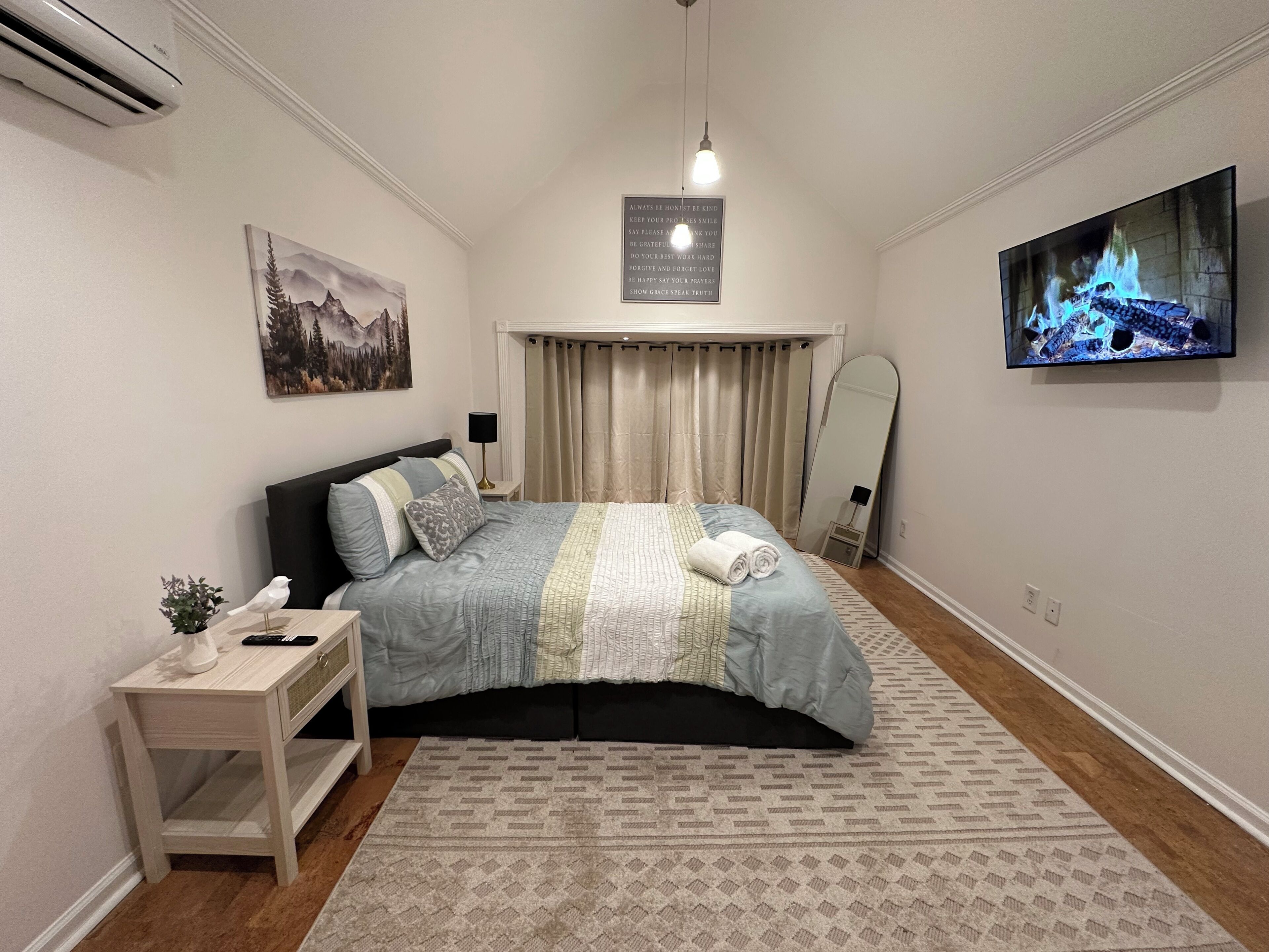 A bedroom with a bed, bedside table, lamp, and a painting on the wall.