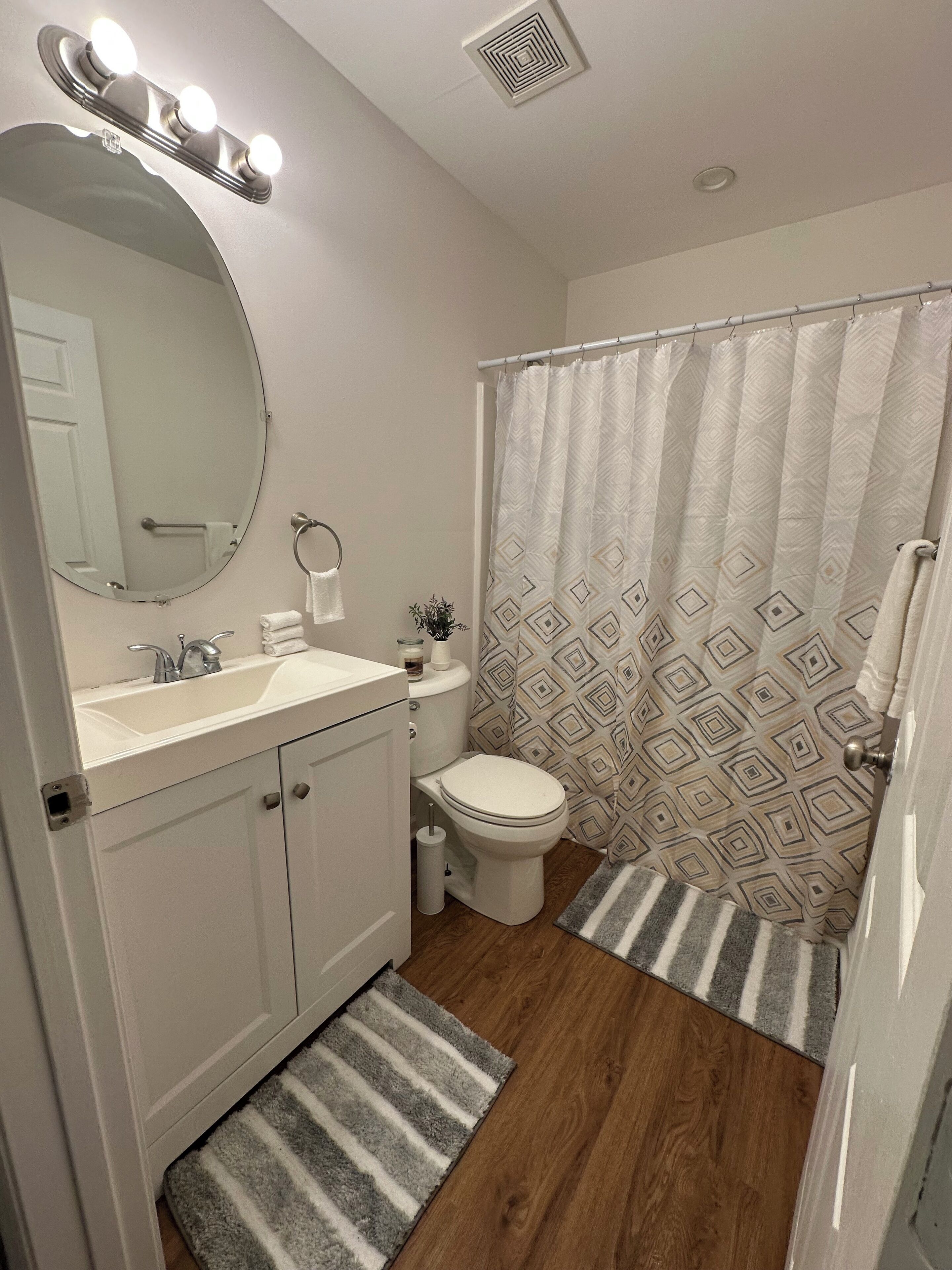 A bathroom with a vanity, sink, mirror, toilet, and shower curtain.