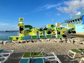 A beach with large green and yellow letters spelling "Bariloche" and a pier in the background. - Paradise on the Rocks - Suite w/Pool View & Balcony #8 (Negril)