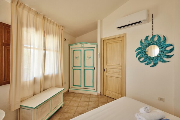 A bedroom with a bed, a bench, a wardrobe, and a mirror on the wall.