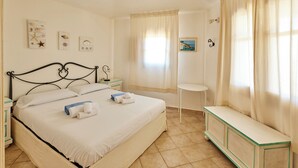 Siististi järjestetty hotellihuone, jossa on sänky, yöpöydät, pieni pöytä ja penkki.