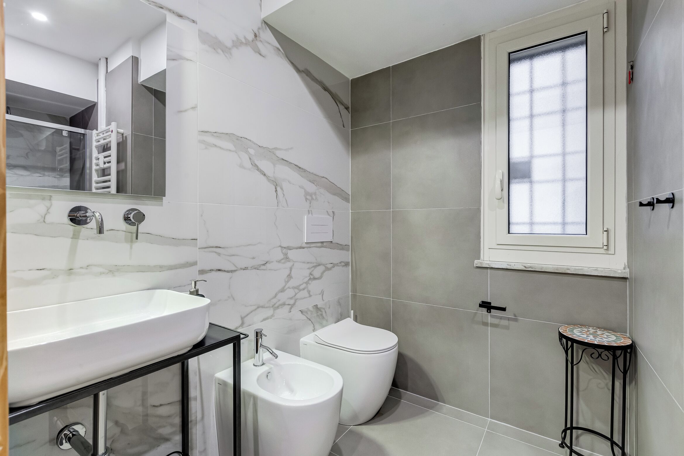 Un baño con un lavamanos blanco, un bidé y un inodoro.