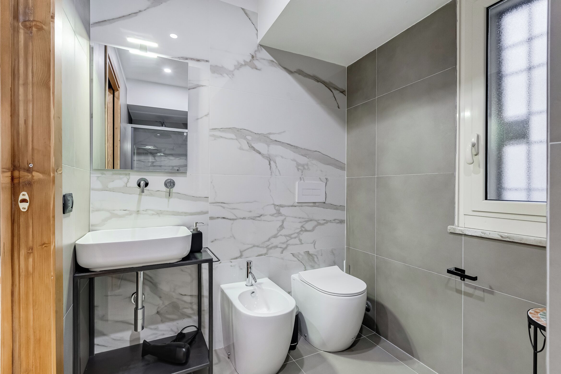 Une salle de bain moderne avec un mur en marbre, un lavabo, un bidet et des toilettes.