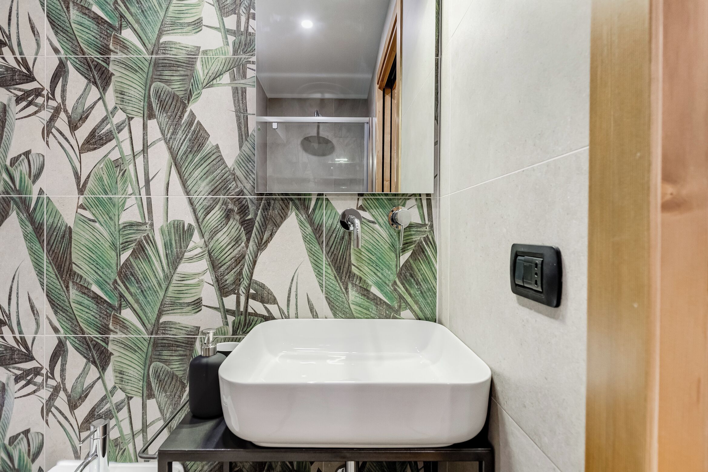 Un baño con lavamanos blanco, un espejo y una zona de ducha.