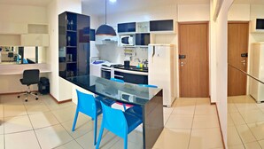 Una cocina moderna con una isla de cristal, sillas azules y un microondas integrado.