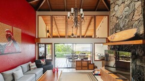 A spacious living area with a grey sofa, wooden coffee table, and a stone fireplace.