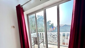 Habitación con puerta de vidrio corredera que da a un área exterior con una silla y una cerca decorativa blanca.