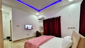 Una habitación de hotel moderna con cama, escritorio, televisión y espejo.