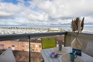 A balcony with a view of a marina, a table with a vase and a book, and a chair. - Horizon Bleu - Superbe vue sur le port (Arcachon)