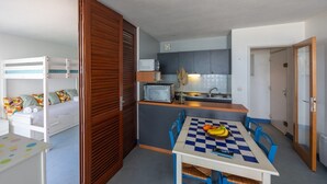 A compact room with bunk beds, a kitchenette, a dining table with chairs, and a small table with a checkered tablecloth. - Horizon Bleu - Superbe vue sur le port (Arcachon)