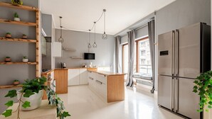 A modern kitchen with a central island, wooden shelves, a built-in oven, and a large refrigerator. - Four Seasons Suite in City Center, 350m from the Sea • 3 Suite - View & Balcony (Pescara)