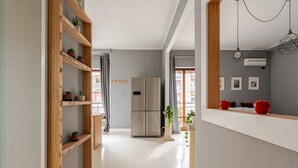 A modern kitchen with a stainless steel refrigerator, wooden shelves with plants, and a window with curtains. - Four Seasons Suite in City Center, 350m from the Sea • 3 Suite - View & Balcony (Pescara)