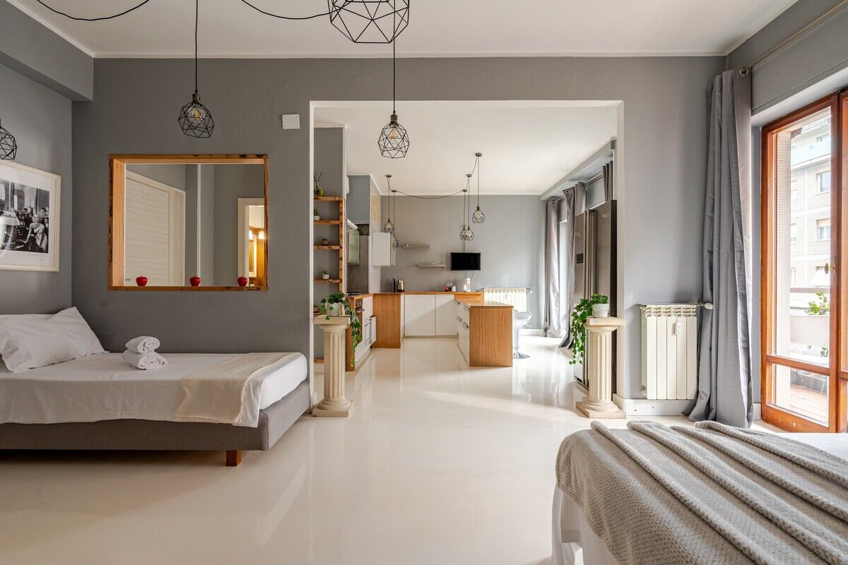 Una moderna camera d'hotel con un letto grande, un'area salotto, una cucina e vista sulla città.