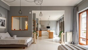 A modern hotel room with a large bed, a sitting area, a kitchen, and a view of the city. - Four Seasons Suite in City Center, 350m from the Sea • 3 Suite - View & Balcony (Pescara)