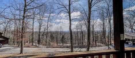 A wooden deck with a view of a forest and mountains in the distance.