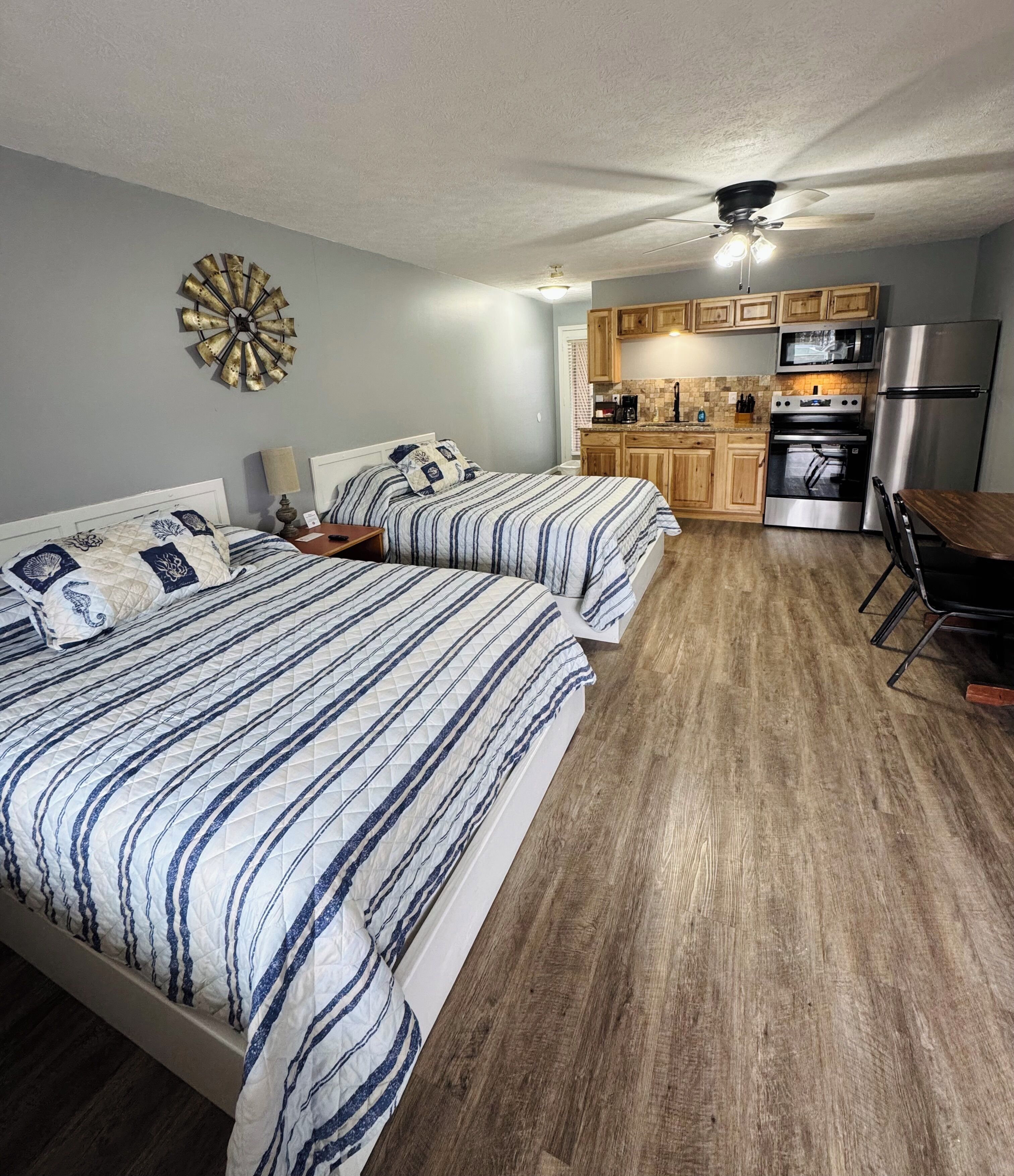 A bedroom with two beds, a kitchenette, and a dining area.