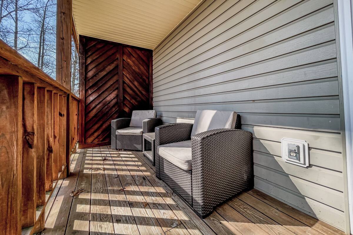 Une véranda avec des meubles en osier et une terrasse en bois.