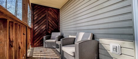 Un porche cubierto con muebles de mimbre y una terraza de madera.