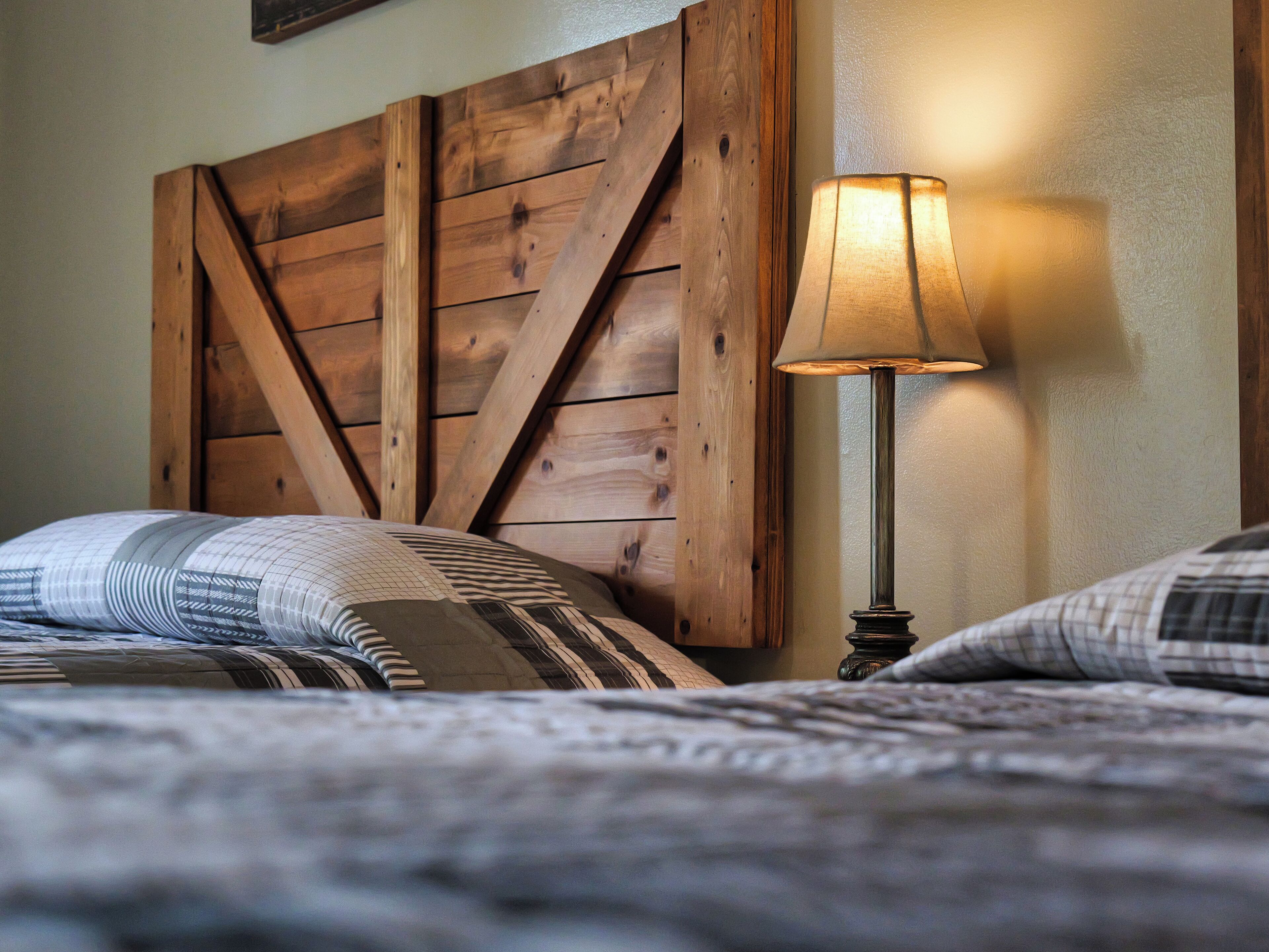 A bedroom with a wooden headboard, a bedside lamp, and patterned bedding.