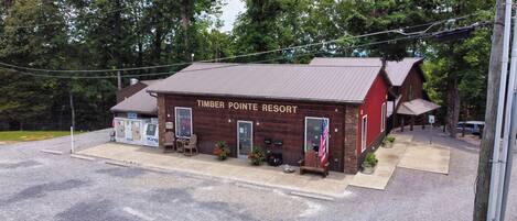 Een rustiek houten gebouw met de naam 'Timber Pointe Resort', een rood dak, een klein terras en een Amerikaanse vlag.