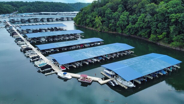 A marina with multiple docks and covered boat slips, surrounded by dense forest. - Timber Pointe Resort (Jamestown)