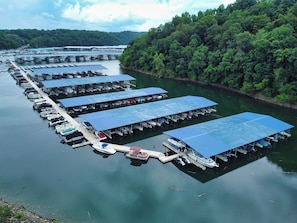 A marina with multiple docks and covered boat slips, surrounded by dense forest. - Timber Pointe Resort (Jamestown)