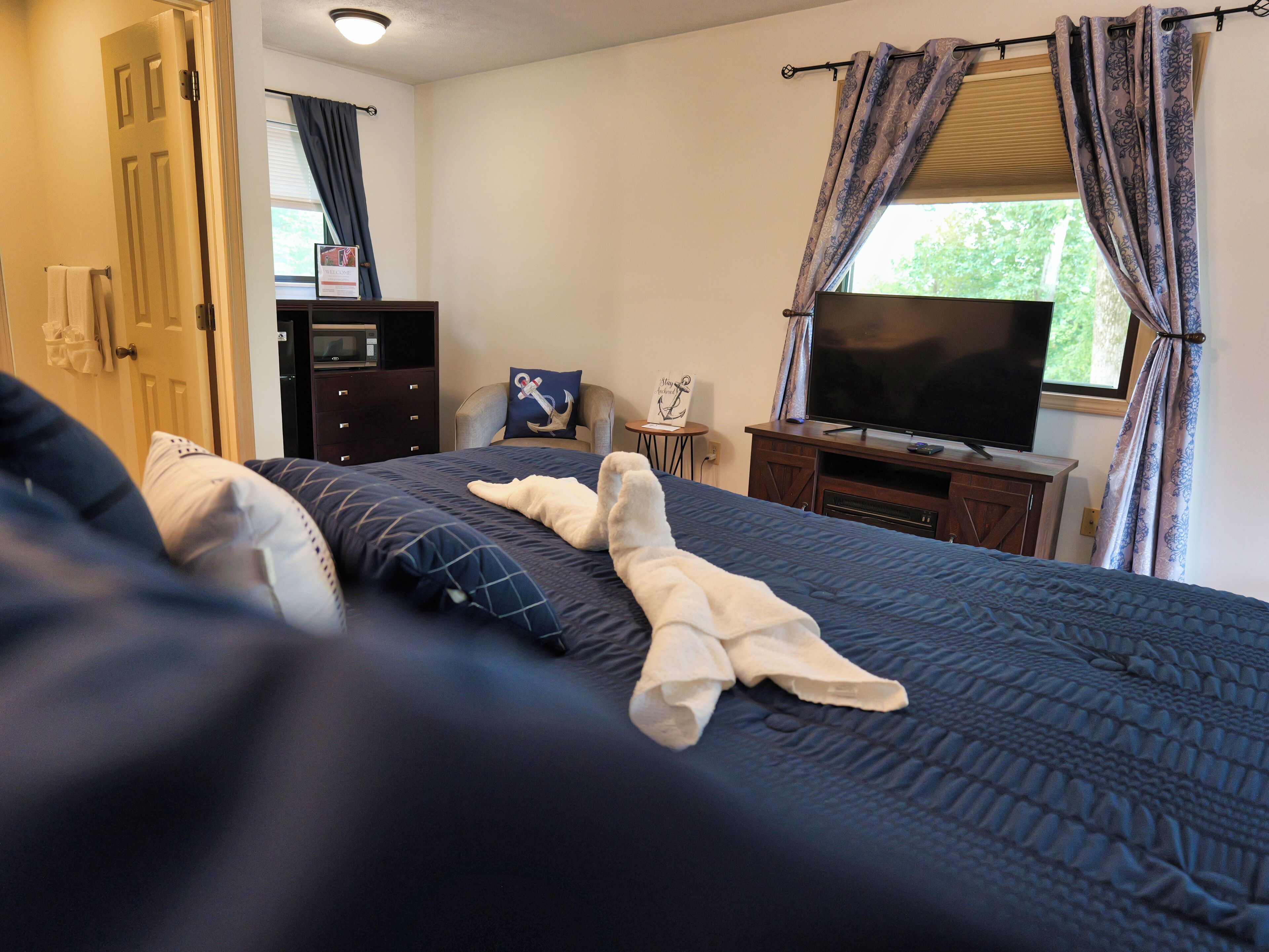 A hotel room with a bed, a TV, a dresser, and a window with curtains.