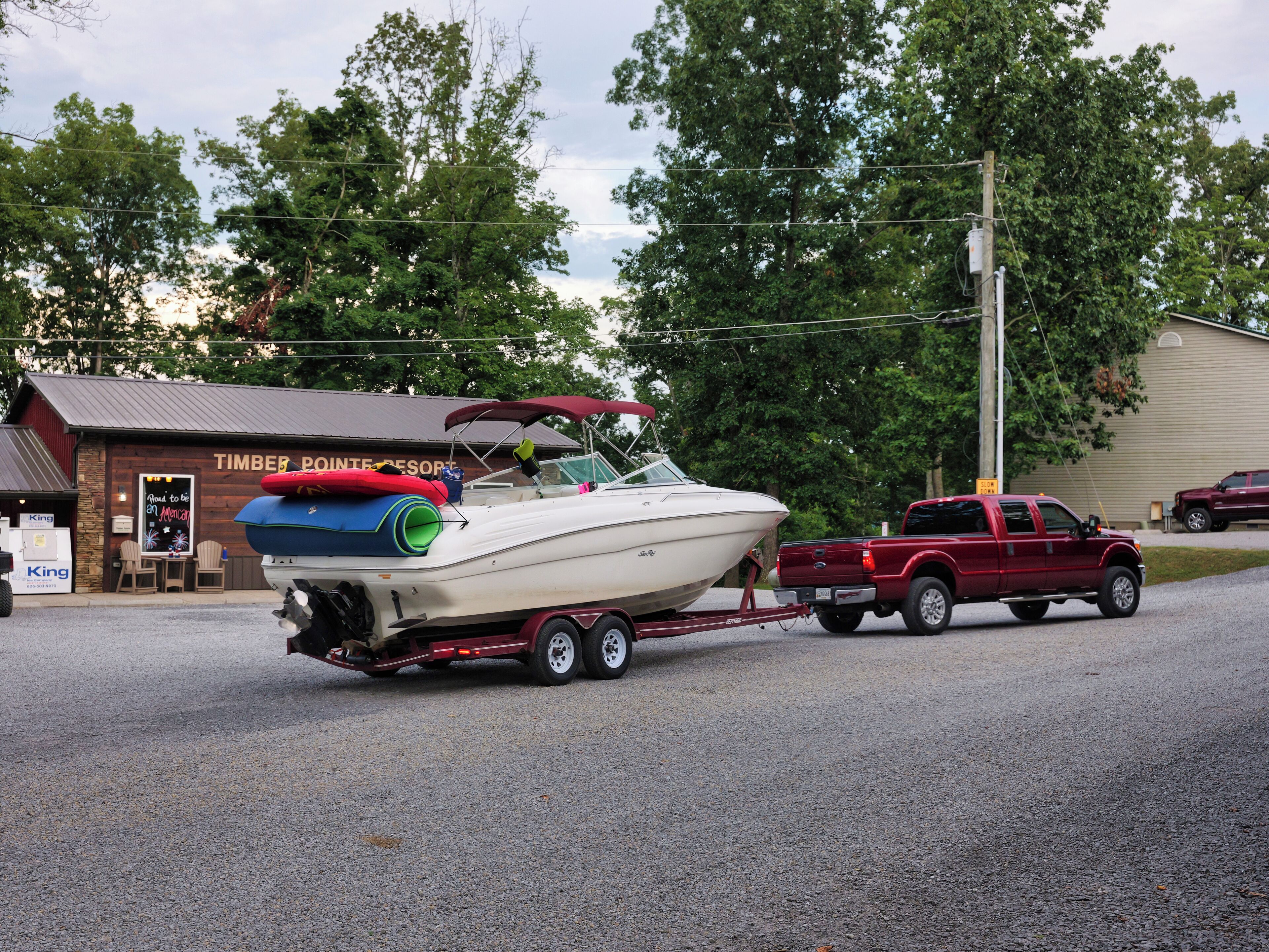 A boat on a trailer being towed by a pickup truck.