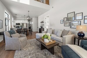 A spacious living area with a high ceiling, a dining area, and a kitchen.