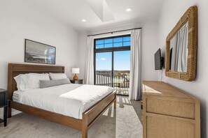 A bedroom with a bed, bedside table, lamp, and a large window with curtains. - Egg Harbor: new build, indoor pool, gym (Egg Harbor)