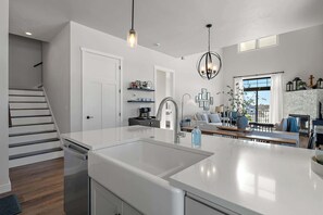 Una cocina moderna con una isla grande, un comedor con vistas y una escalera.