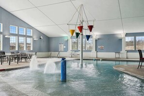 A swimming pool with a water fountain, seating area, and large windows. - Egg Harbor: new build, indoor pool, gym (Egg Harbor)