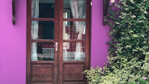 Une porte en bois avec des panneaux de verre, placée devant un mur violet.