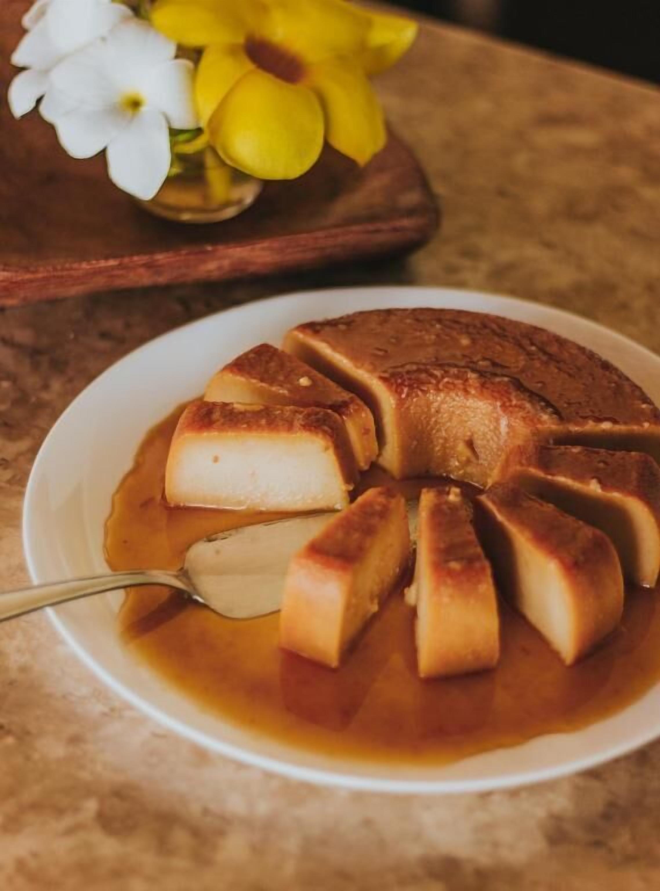 A caramel flan on a plate with a spoon.