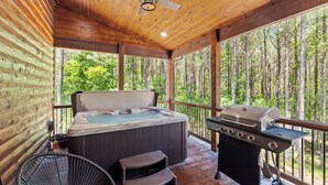 Eine Holzterrasse mit Whirlpool und Grill.