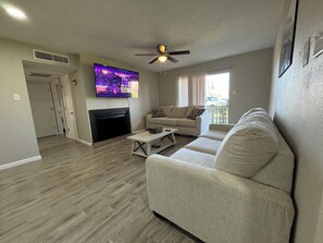 A living room with a fireplace, a ceiling fan, and a television mounted on the wall. - Glenmeadow Retreat 2BR Sleeps 6! (Beaumont)
