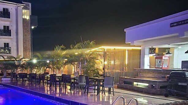 Un área junto a la piscina con mobiliario exterior y una parrilla.