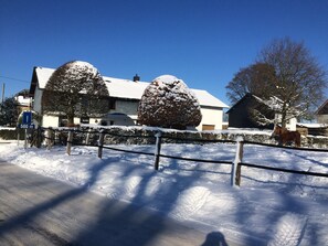 A snow-covered landscape with a house, a horse, and a sign indicating a 500-meter distance. - Holiday Home for 8 People in Butgenbach (Buetgenbach)