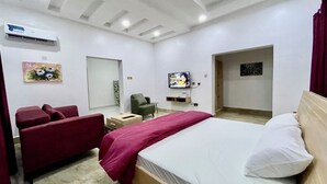 Ein Hotelzimmer mit einem Bett, einem roten Sofa, einem Fernseher und einem kleinen Tisch.