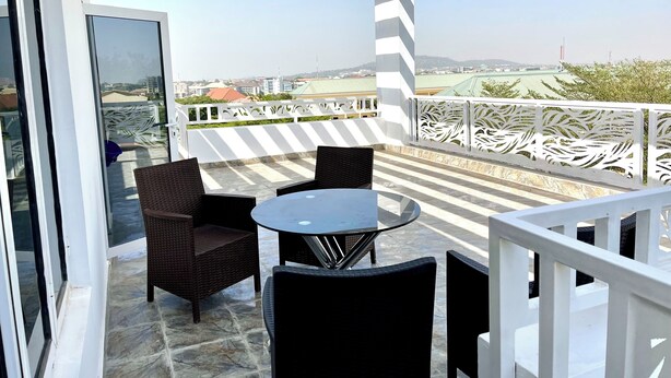 Ein Balkon mit Tisch und Stühlen, Blick auf die Stadt, und ein weißes Geländer.
