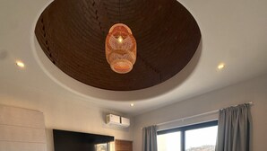 A modern bedroom with a large bed, a flat-screen TV mounted on the wall, and a ceiling light fixture. - Desert Retreat: Heated Salt Water Plunge Pool* Grill, Views, Cinema,nearBalandra (La Paz)