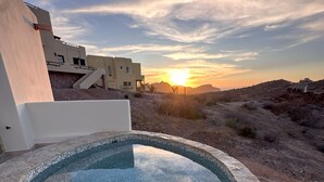 A swimming pool with mosaic tiles, surrounded by stone walls, set against a sunset with buildings in the background. - Desert Retreat: Heated Salt Water Plunge Pool* Grill, Views, Cinema,nearBalandra (La Paz)