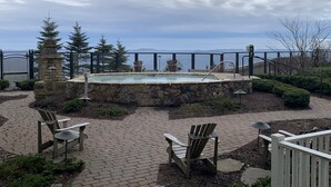 A pool area with a stone wall, wooden chairs, and a view of the mountains. - NEW! Seneca 113: Private Entrance, Hot Tub, Heated Garage, Sleeps 6! (Snowshoe)