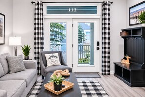 A modern living room with a grey sofa, a black coffee table, and a black entertainment unit. - NEW! Seneca 113: Private Entrance, Hot Tub, Heated Garage, Sleeps 6! (Snowshoe)