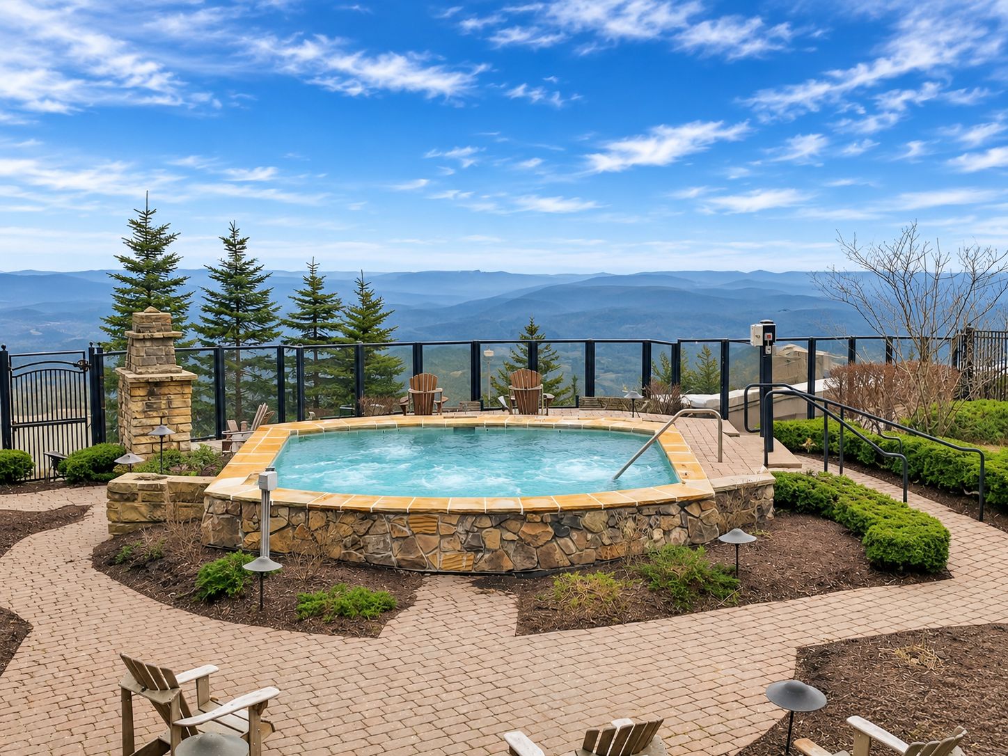 A hot tub surrounded by stone walls, with a view of mountains in the background.