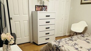 A bedroom with a bed, a dresser, a chair, and a wardrobe.
